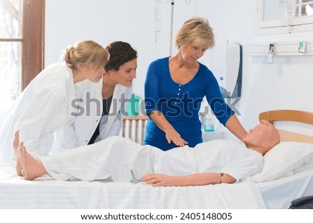 nurses training with dummy on bed Royalty-Free Stock Photo #2405148005