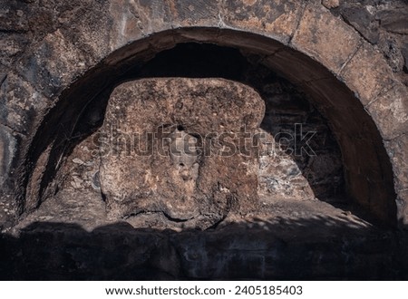 Old street water fountain with the woman face photo. Mascaron in the stone wall niche. Sant Miquel del Fai monastery photography. High quality picture for wallpaper, article