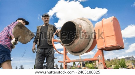 concrete mixer and a male worker working during the day in the summer.