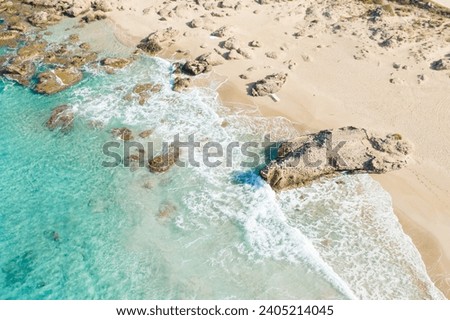 The sandy beach at the foot of the rocky cliffs in the arid countryside , in Europe, Greece, Crete, towards Kissamos, towards Chania, By the Mediterranean Sea, in summer, on a sunny day. Royalty-Free Stock Photo #2405214045