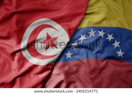 big waving national colorful flag of venezuela and national flag of tunisia . macro