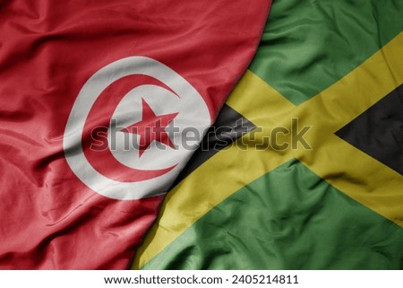 big waving national colorful flag of jamaica and national flag of tunisia . macro
