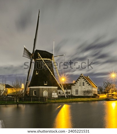 long shuttertime Night picture of a windmill reflected in the water with the house of the miller located in schipluiden
