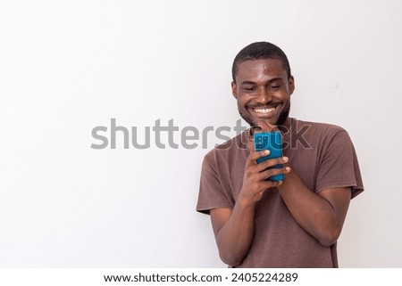 Young african black man looking at mobile phone feeling joyful. Technology, Wireless technology Royalty-Free Stock Photo #2405224289