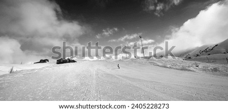 Snowboarder on snowy ski slope in winter day. Georgia, region Gudauri. Caucasus Mountains. Black and white toned landscape. Wide angle panoramic view.