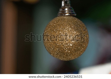 Glittery golden Christmas bauble hanging on a tree