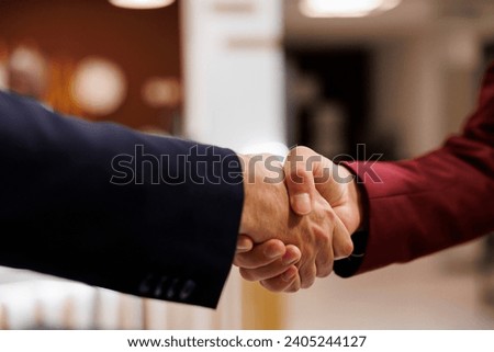 Entrepreneurs agreeing upon collab together, successful important meeting at hotel abroad. Business professionals shaking hands to mark the beginning of a fruitful partnership. Close up. Royalty-Free Stock Photo #2405244127