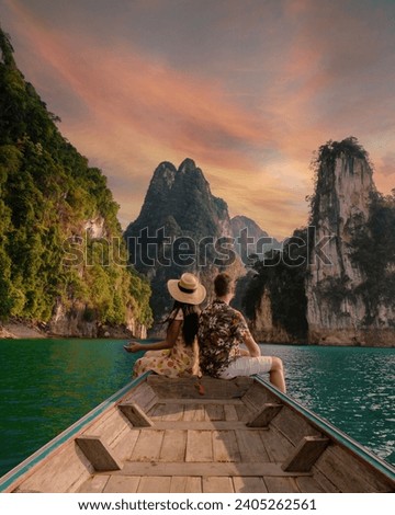 A couple of men and women in front of a longtail boat in Khao Sok Thailand, Scenic mountains on the lake in Khao Sok National Park South East Asia at sunset Royalty-Free Stock Photo #2405262561