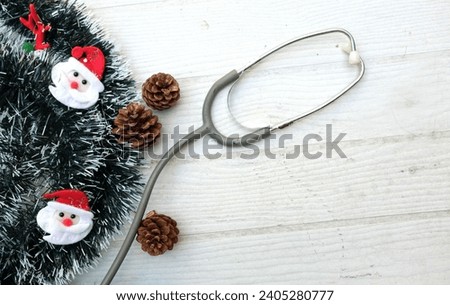 Christmas decoration frame from decorated green fir branches of a Christmas tree and cute snowman,stethoscope isolated on a white wooden table backdrop. Empty place for text . Banner backdrop Xmas