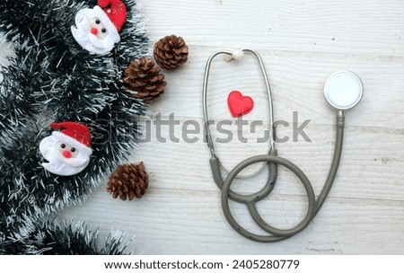 Christmas decoration frame from decorated green fir branches of a Christmas tree and cute snowman,stethoscope isolated on a white wooden table backdrop. Empty place for text . Banner backdrop Xmas