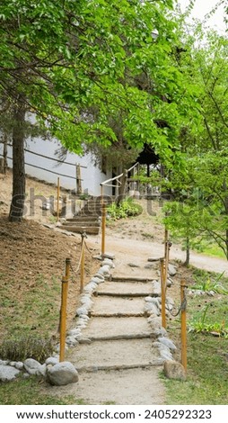Stairs leading to country house through garden. Bushcraft looking stairs with gentle slope, followed by more solid higher incline stairs.  Branches of trees are in the way Royalty-Free Stock Photo #2405292323