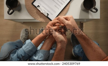 Top view of married couple at the therapy session. Close up shot of man and woman on the sofa holding hands together, supporting each other.
