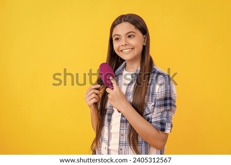 cheerful teen girl brushing hair with hairbrush. Beautiful teen girl with hairbrush. teen girl using hairbrush to style hair isolated on yellow. teen girl holding hairbrush while brushing her hair