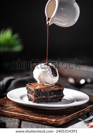 Brownie with vanilla ice cream, Chocolate sauce dripping on vanilla ice cream with brownie, placed on white plate