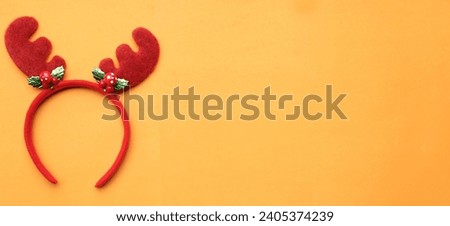 cute christmas headbands with funny red deer horns isolate on a orange backdrop. concept of joyful christmas party,new year is coming soon, festive season decoration with christmas elements