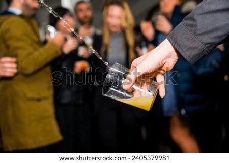 Detail of a hand holding a glass of apple cider at an event in a cider house, Basque Country Royalty-Free Stock Photo #2405379981