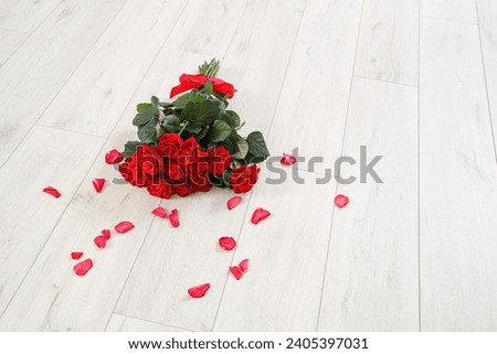 Bouquet of beautiful red roses and petals on wooden floor. Valentine's Day celebration Royalty-Free Stock Photo #2405397031