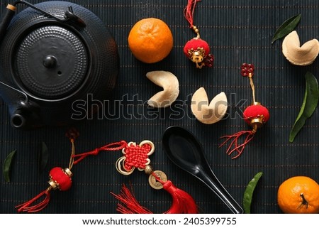 Black bamboo mat with teapot, fortune cookies and Chinese symbols, closeup. New Year celebration