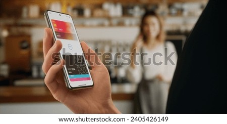 CU Man is paying with a card linked to his smartphone at the cafe using wireless NFC technology Royalty-Free Stock Photo #2405426149