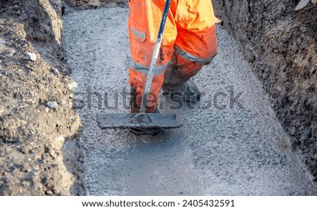 Concrete cast-in-place work. Builder leveling wet concrete. Concrete works on building construction site Royalty-Free Stock Photo #2405432591