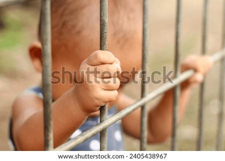 close up of toddler's hand holding the fence