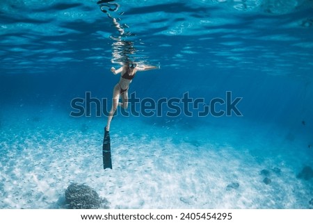 Woman with fins swimming over sandy sea. Freediver in blue ocean in Hawaii Royalty-Free Stock Photo #2405454295