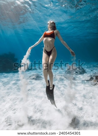 Freediver swims underwater and playing with sand. Freediving with attractive woman in tropical blue ocean Royalty-Free Stock Photo #2405454301