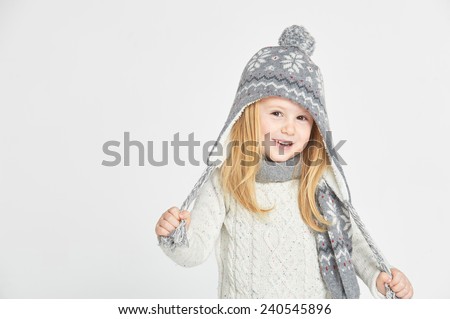 Beautiful blond girl playing in the winter warm hat and scarf on a white background