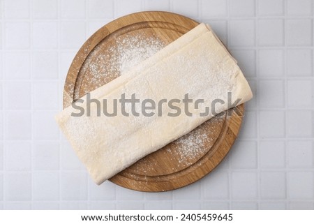 Raw puff pastry dough on white tiled table, top view Royalty-Free Stock Photo #2405459645