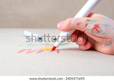 Unrecognizable child drawing felt-tip pens on the sofa or a carpet. Daily life stain concept. High quality photo