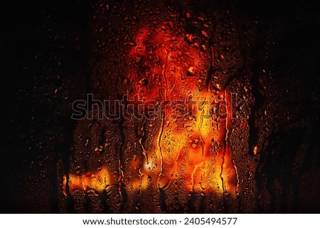 Raindrops on the window. Drops of water on the glass. Abstract background. Fire flame. Texture of drops. Selective soft focus