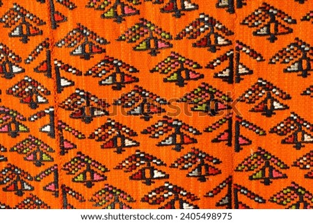Orange fabric with a pattern of black geometric shapes.