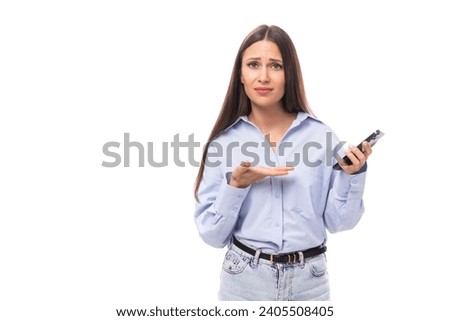 young charming european business woman with long black hair dressed in a blue blouse is waiting for a call on the phone on a white background with copy space