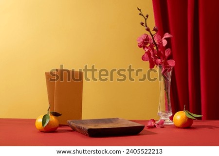 Wooden dish with vacant space arranged with glass pot of flowers. Envelopes and tangerines featured. Lunar New Year in China has a history of more than 4,000 years