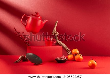 A pot of tea is suspended, a tea cup is placed on a red platform, a plate of jam, tangerines and decorations displayed on a red background. The atmosphere of Tet is brilliant.