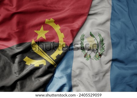 big waving national colorful flag of guatemala and national flag of angola . macro