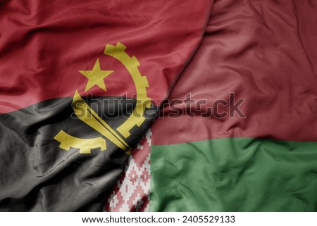 big waving national colorful flag of belarus and national flag of angola . macro