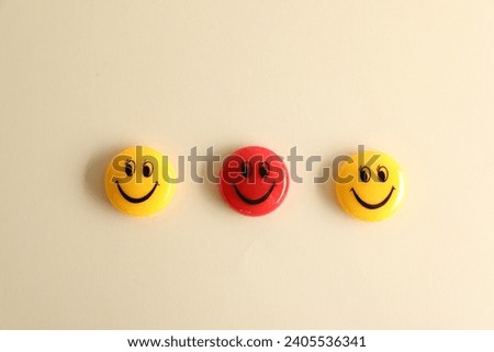 Choice concept. Red and yellow magnets with happy emoticons on beige background, flat lay