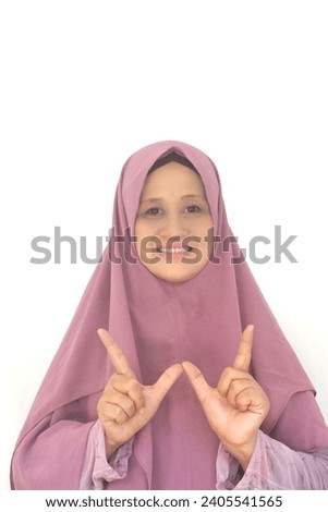 Beautiful woman wearing hijab with letter W finger sign language and friendly expression. Selective focus.