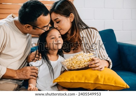 In their comfortable living room family enjoys quality time watching TV with popcorn. father mother daughter and sibling are all smiles fostering togetherness and happiness.