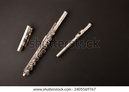 General view of a metal flute disassembled into parts isolated on black background. Top view.