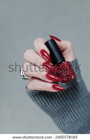 hands with long nails and a bright red and black manicure	