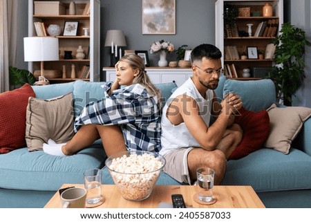 Stressed young married couple sitting separately on different sides of sofa ignoring each other after quarrel. Offended spouses not talk communicate feeling depressed disappointed after argue.