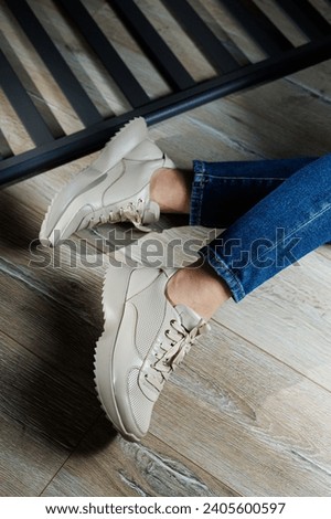Collection of women's leather shoes. Female legs in leather beige casual sneakers. Stylish women's sneakers.