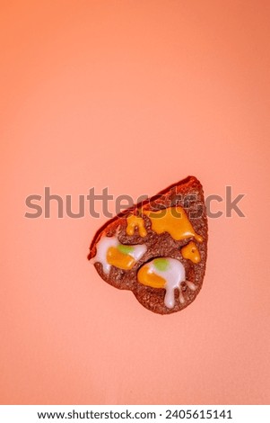 Colorful heart-shaped cookie-gingerbread on a pink background for Valentine's Day. Heart-shaped gingerbread on a pink background. Love and prosperity. Gingerbread with a frosted face.