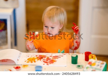 Child toddler paints in an album on paper, finger paints, child development