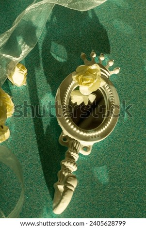 Romantic composition in green, blue, cream color, roses, little mirror and decorative ribbons with bright reflexions. 