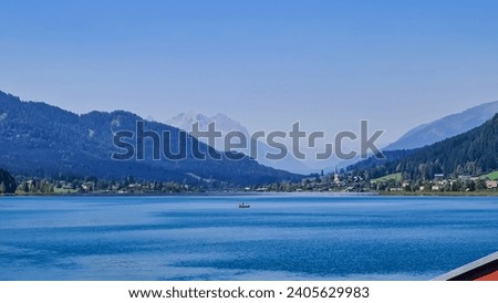 Scenic view of east bank of alpine lake Weissensee in Gailtal Alps, Carinthia, Austria. Bathing lake surrounded by mountain ranges of Austrian Alps. Serene landscape amidst untouched nature in summer Royalty-Free Stock Photo #2405629983
