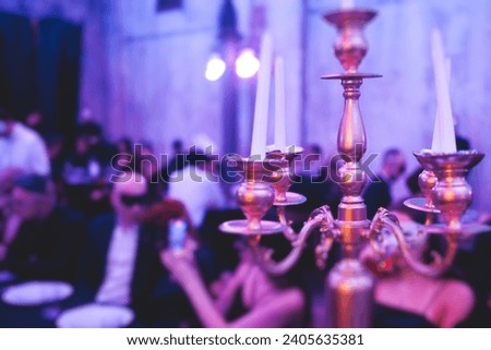 Vintage retro brass candlesticks with candles burning, luxury event banquet table setting decoration in a restaurant hall, atmosphere with  a candleholder, candle fire with guests on masquerade party Royalty-Free Stock Photo #2405635381