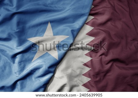 big waving national colorful flag of qatar and national flag of somalia . macro